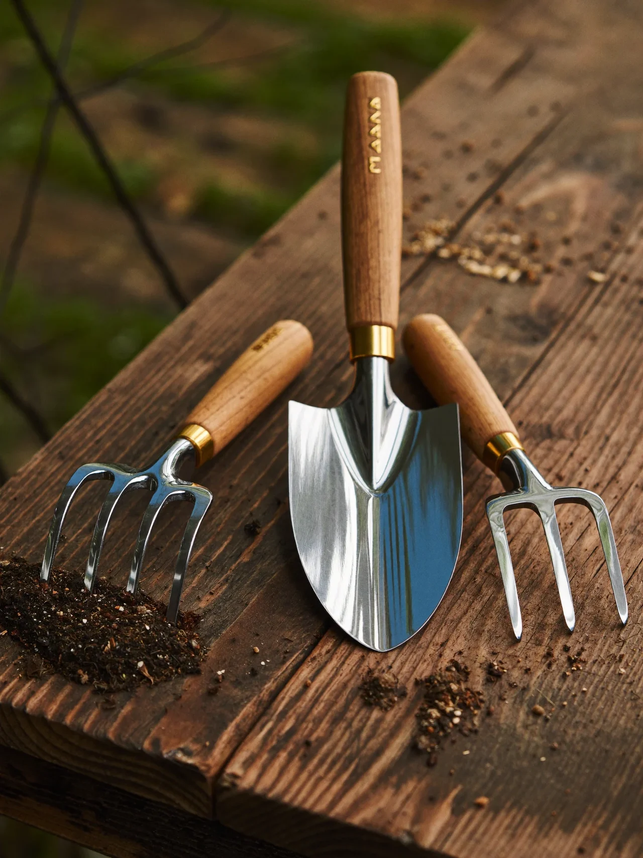 Gartenkelle, Gartenschere und Handgabel auf einer verwitterten Werkbank aus Holz, illustrativ